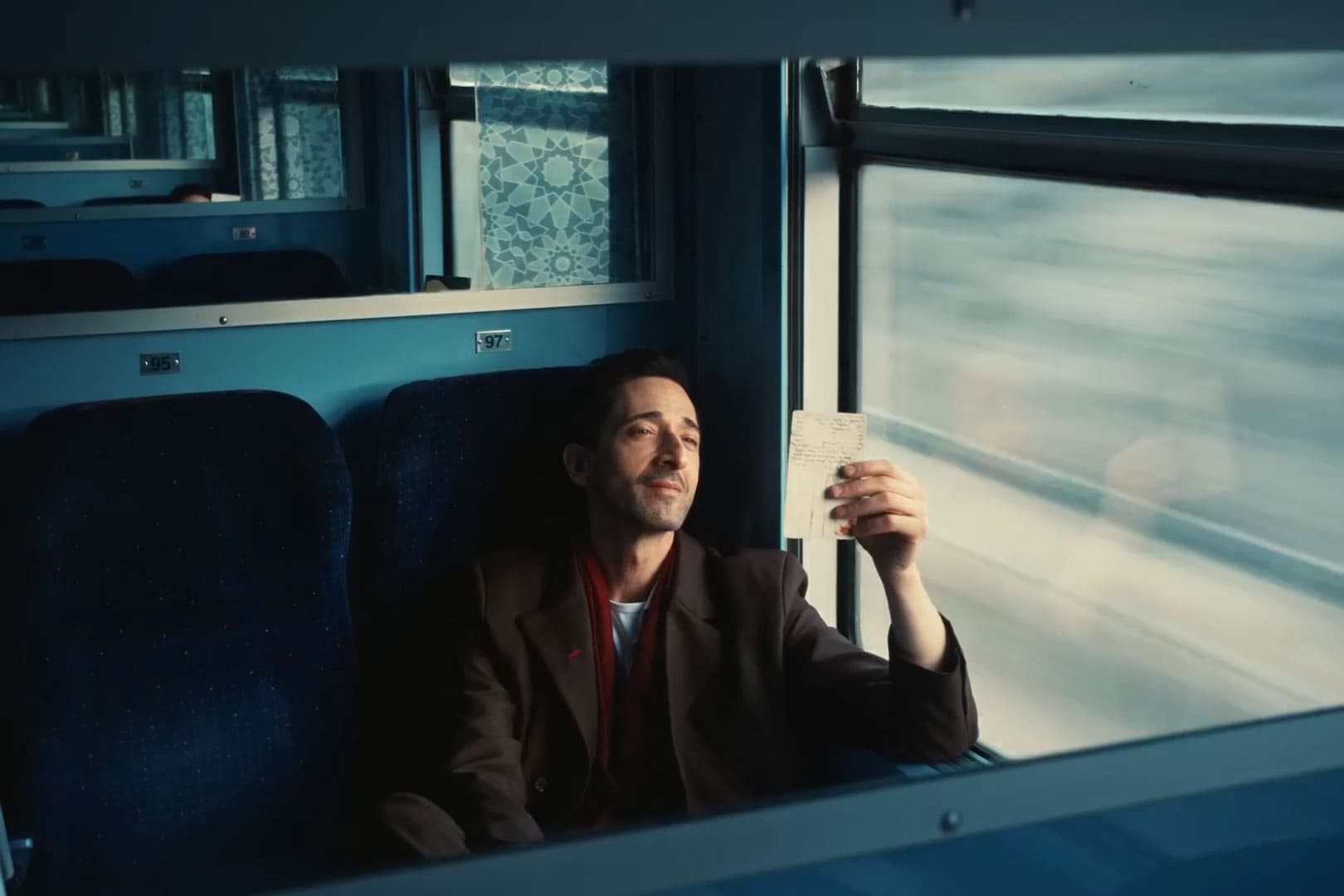 Sentado no trem - Adrien Brody estrela campanha de malas da Monos